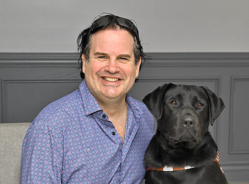 Christian and black lab guide dog Gideo sit close indoors for grad portrait