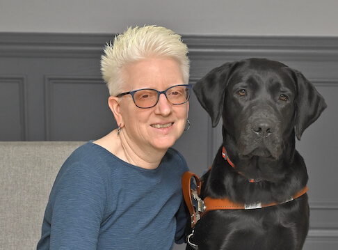 Pamela leans closeto black Lab guide dog Mary for their team portrait