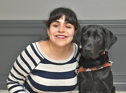 Mari leans into black Lab guide dog Betty for their team portrait