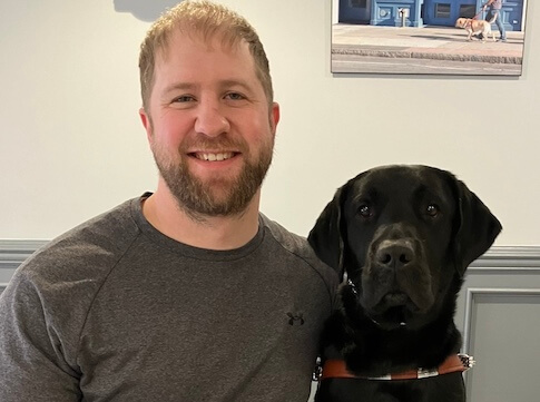 Ethan sits next to black Lab guide dog Archer for their team portrait