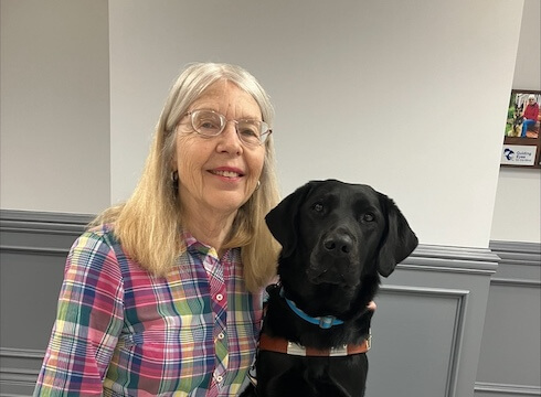 Deborah and black lab guide dog Giada sit for their team portrait.