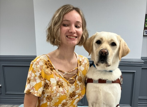 Jaylen and yellow Lab guide dog Carly sit for their team portrait