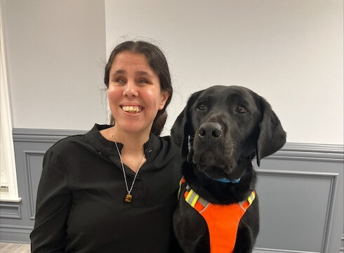 Paulina and black Lab guide dog Ophelia sit close for their team portrait