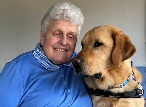 Carla and yellow lab guide dog Biscotti sit with heads together with contented expressions