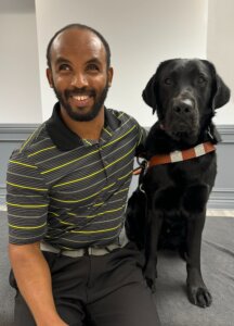 Lucas sits beside his black Lab guide dog Watson for their team portrait.