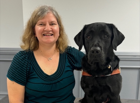 Anita sits beside her black Lab guide dog Nikolai for their team portrait.