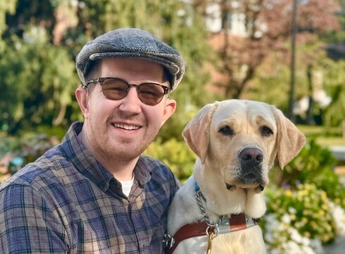 Hunter sits on a landscaped terrace next to yellow lab guide dog Parfait for their team portrait