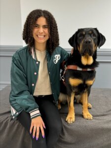 Emily sits beside her black & tan Lab guide dog Patch for their team portrait.