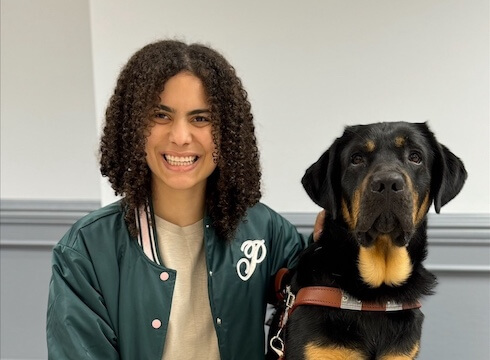 Emily sits beside her black & tan Lab guide dog Patch for their team portrait.