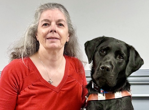 Evelyn sits with black lab guide dog Lenora for their team portrait