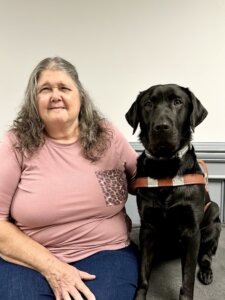 Irene and black Lab guide dog Timothy sit side by side for team portrait