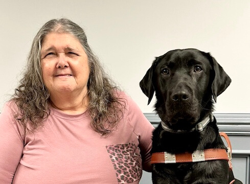 Irene and black Lab guide dog Timothy sit side by side for team portrait