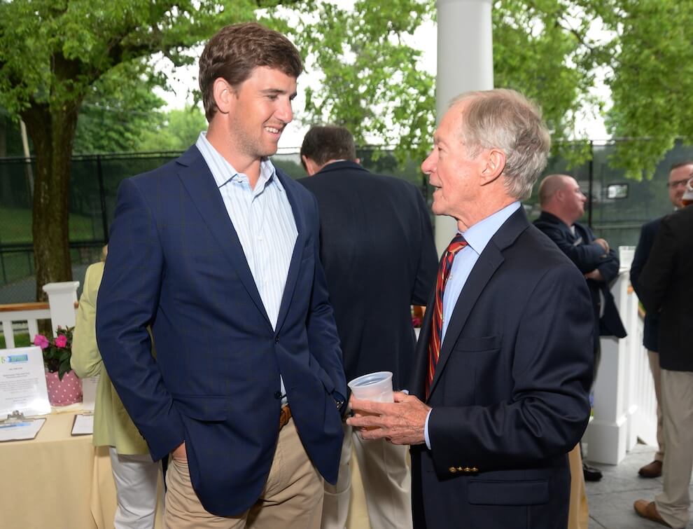 At a Golf outing Bill speaks with future Board Member Eli Manning on the veranda in a casual pose