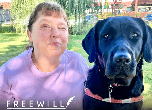 Sonia is lavender shirt next to black guide dog Petal with FreeWill logo in bottom left corner