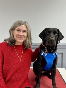 Carolyn sits with black Lab guide dog Yola for their team portrait