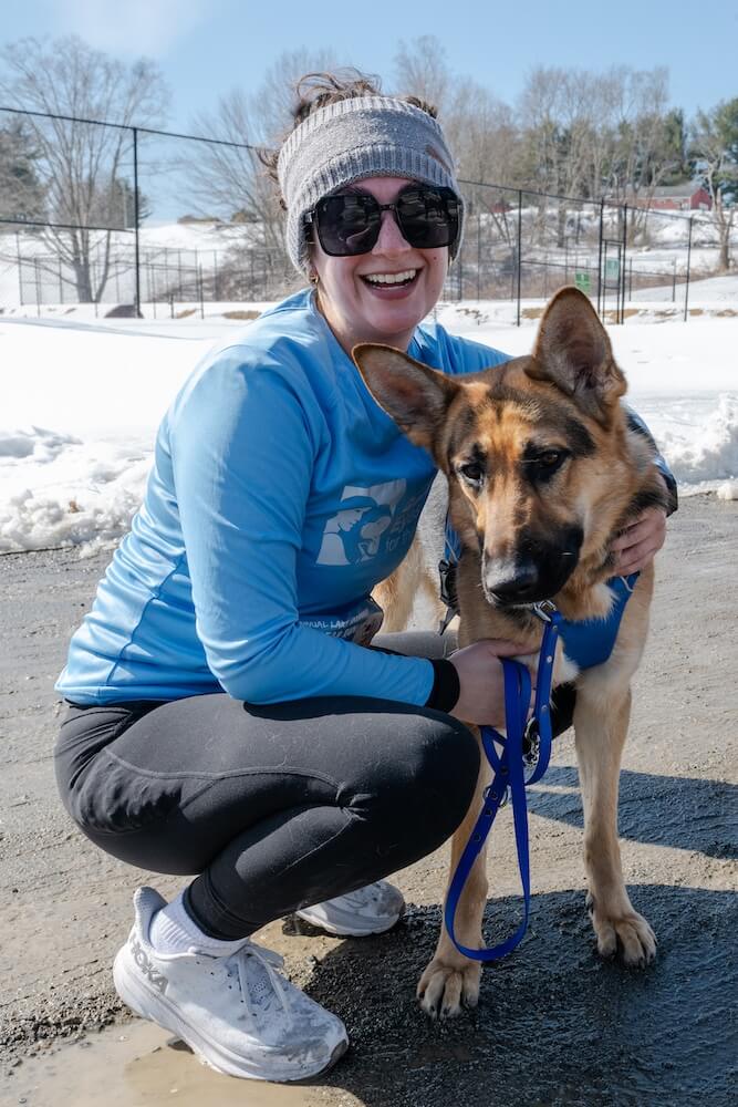 GDMI Trainee Jenna squats next to guide dog in training German Shepherd Waltz with her arm around her