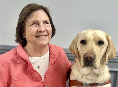 Beth and yellow Lab guide dog Calypso sit together for their graduate team portrait