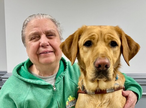 Sharlene and yellow Lab guide dog Hollywood sit side by side for their indoor team portrait